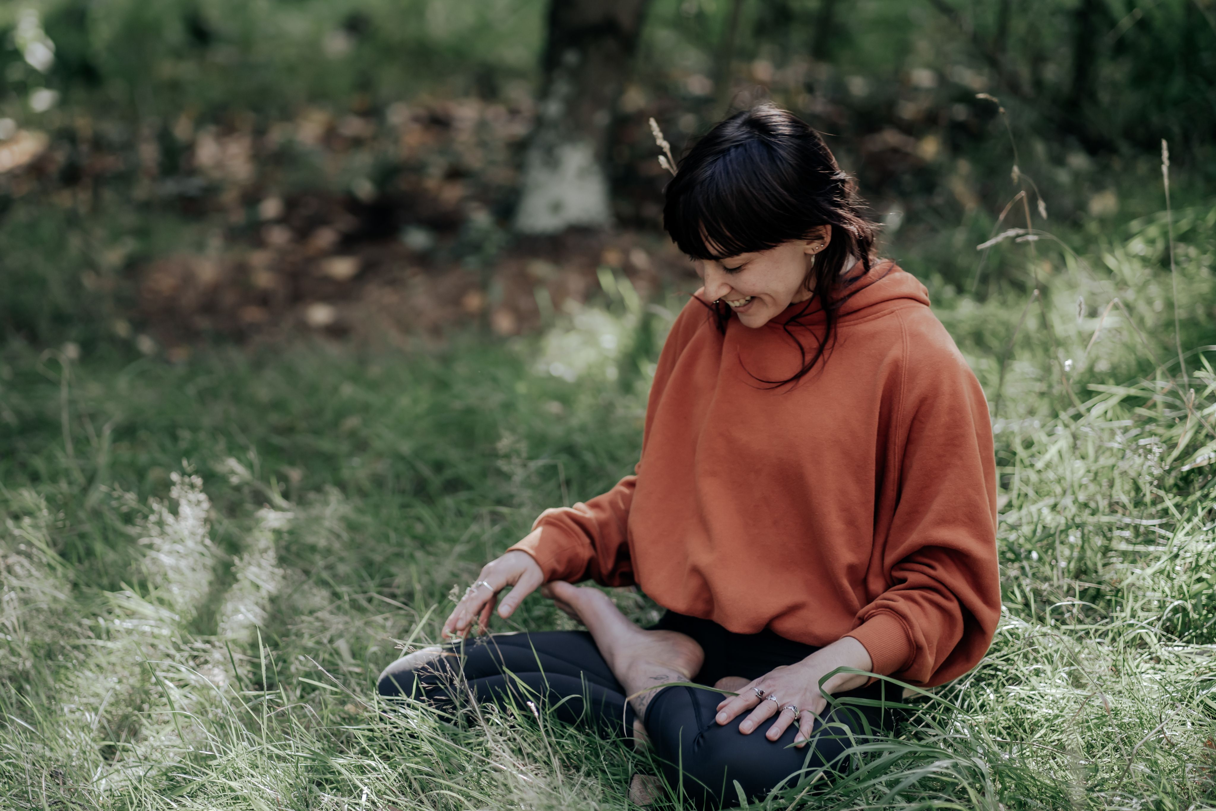 Becca sitting cross legged on some grass.