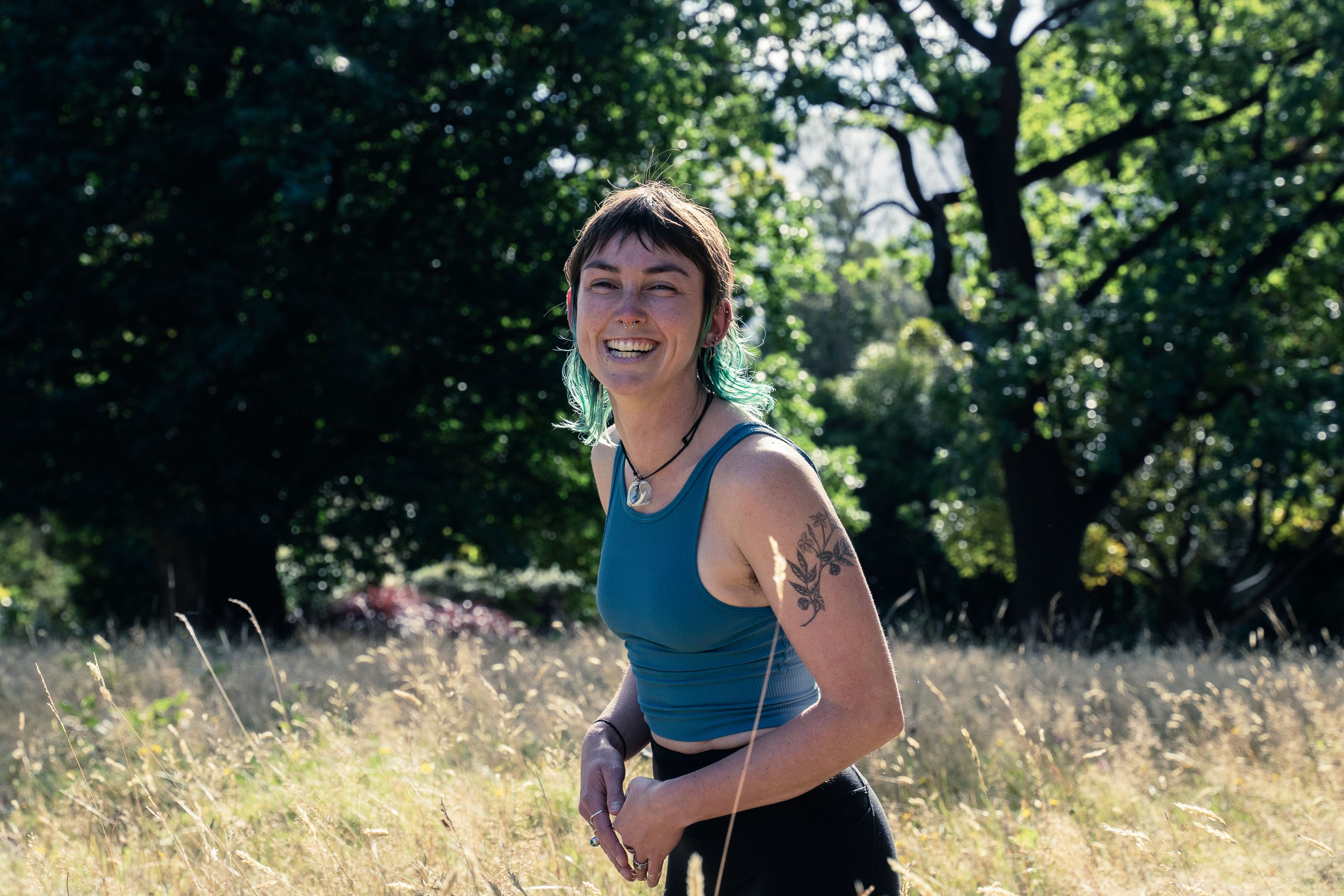 Becca smiling at the camera, while standing in some long grass.
